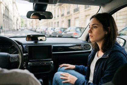 Jeune femme en cours de conduite accompagnée dans une auto-école, regardant la route avec concentration