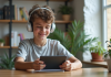 Jeune garçon avec casque et T-shirt regardant une tablette éducative